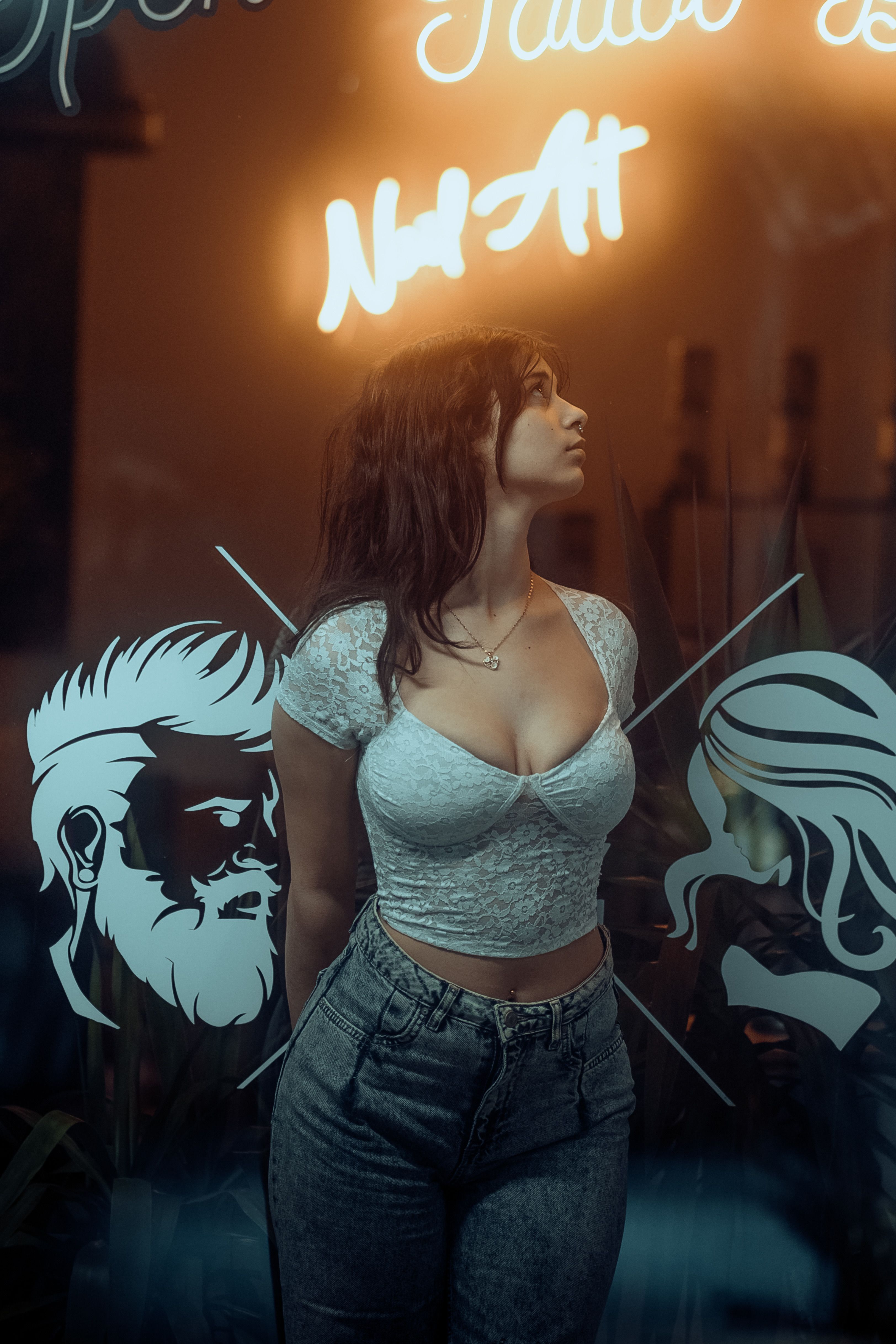 Woman standing in front of a barber shop window with neon lights.