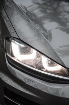 A close-up view of a modern car headlight with reflections.