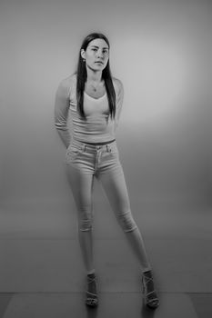 Black and white photo of a young woman posing confidently in a studio setting.