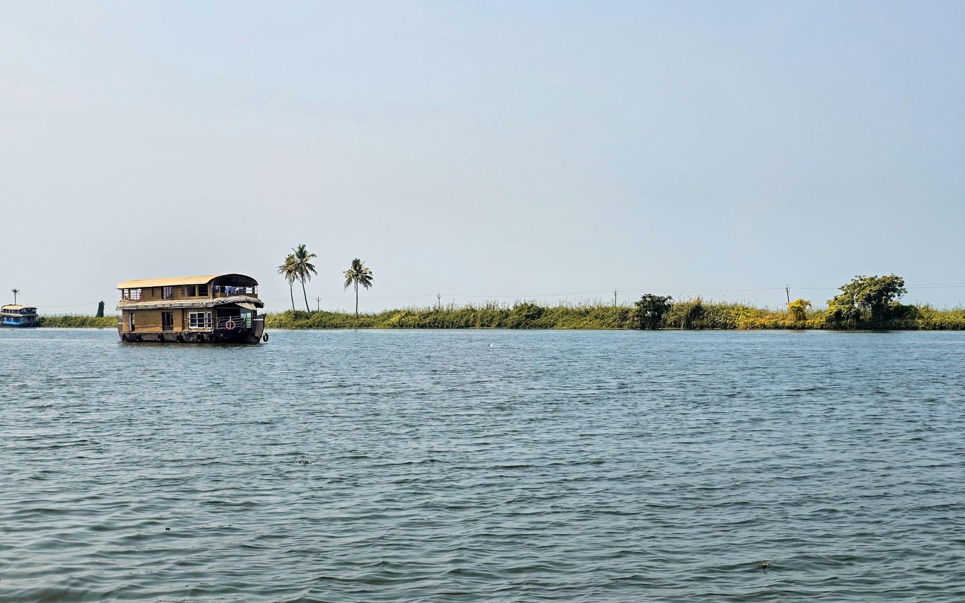 A tranquil houseboat floats on the scenic Alappuzha backwaters in Kerala, India.
