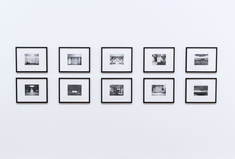 Ten black-and-white framed prints on a white gallery wall
