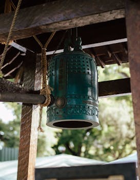 An intricately designed bronze bell hanging in a serene Buenos Aires garden.