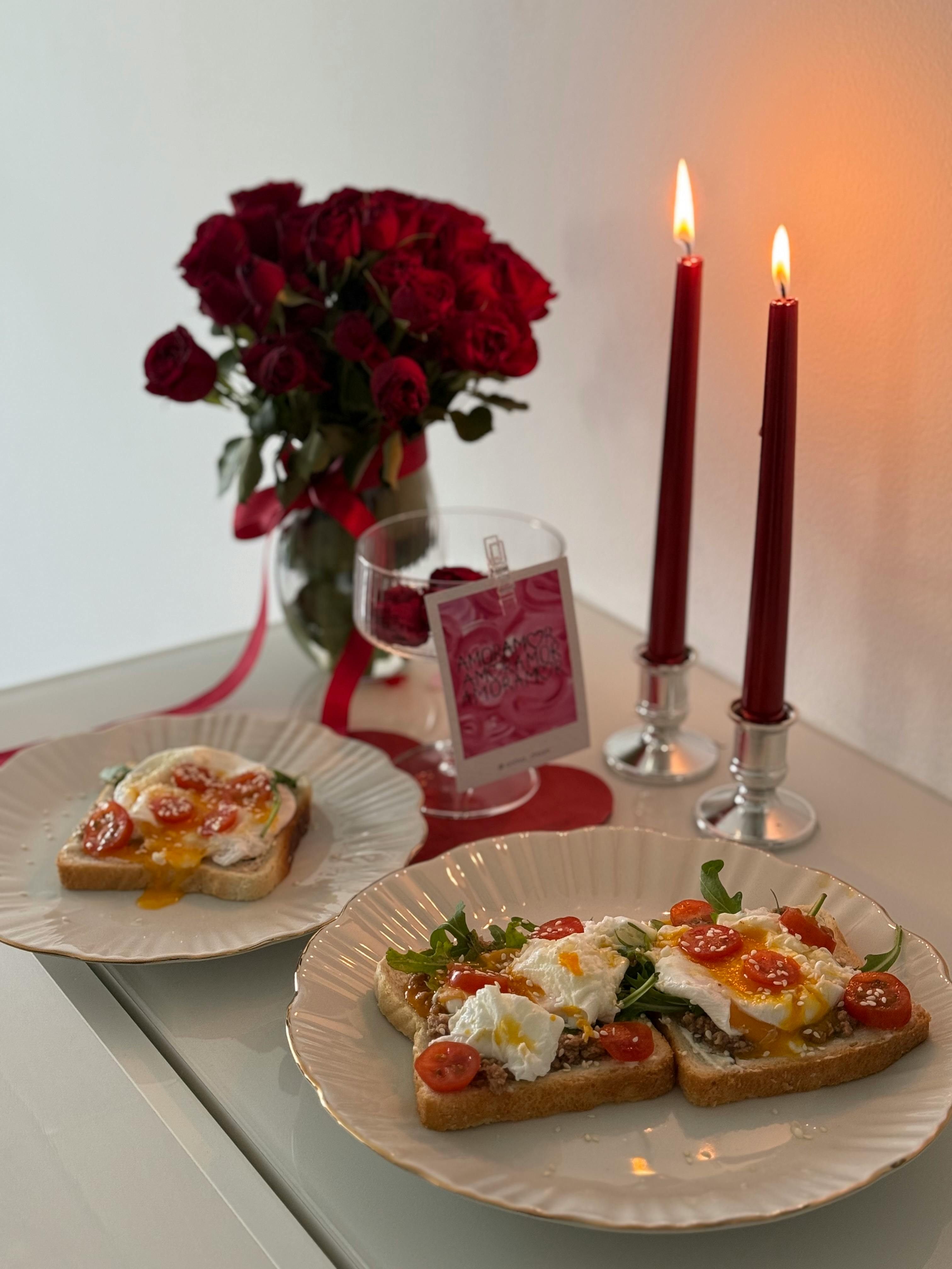 Elegant breakfast with poached eggs, roses, and candles creates a romantic atmosphere.
