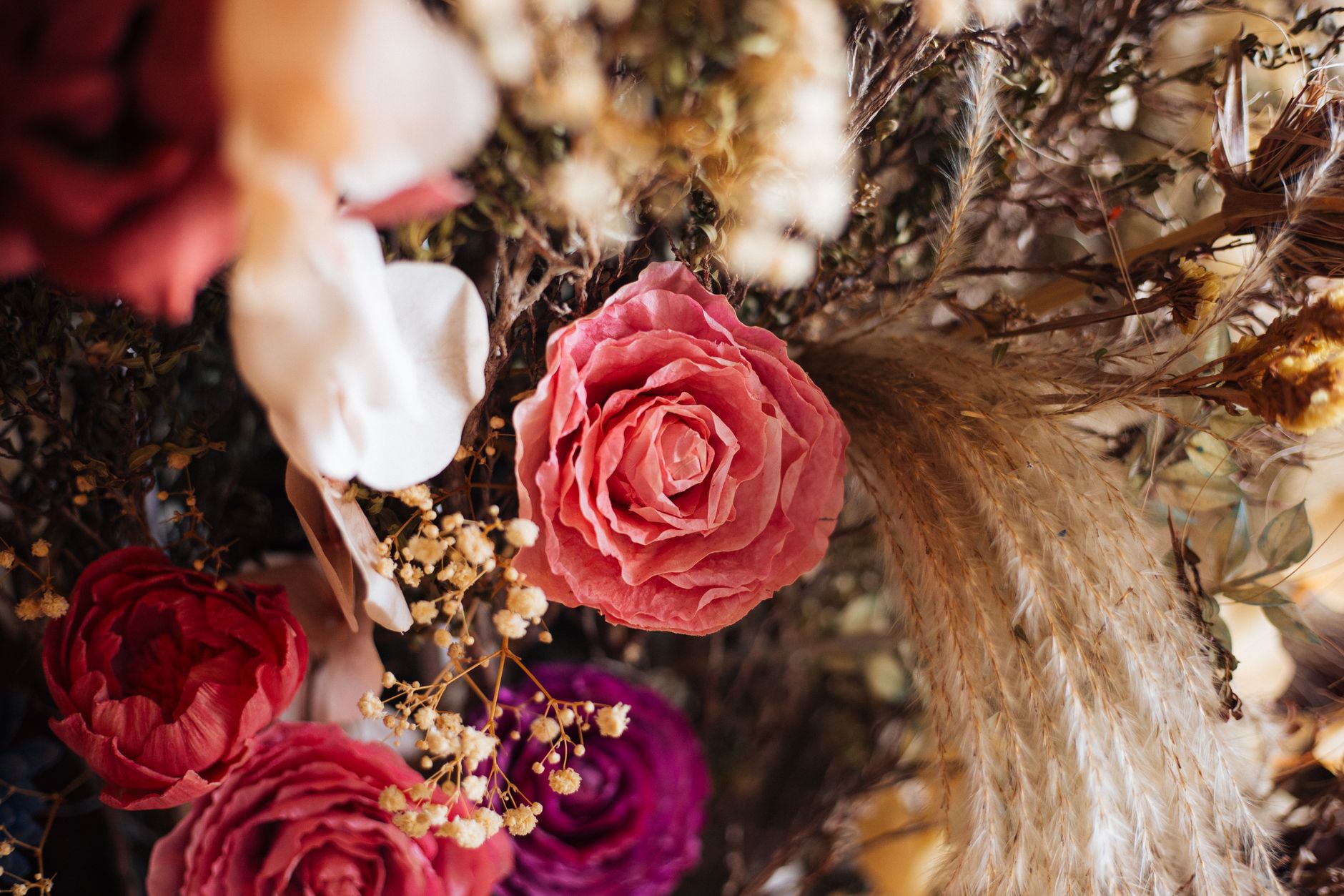 Close-up of a stunning floral arrangement featuring vibrant roses and pampas grass.