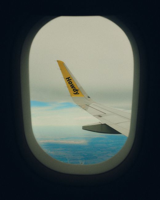 View from airplane window capturing a scenic aerial view through the wing tip.