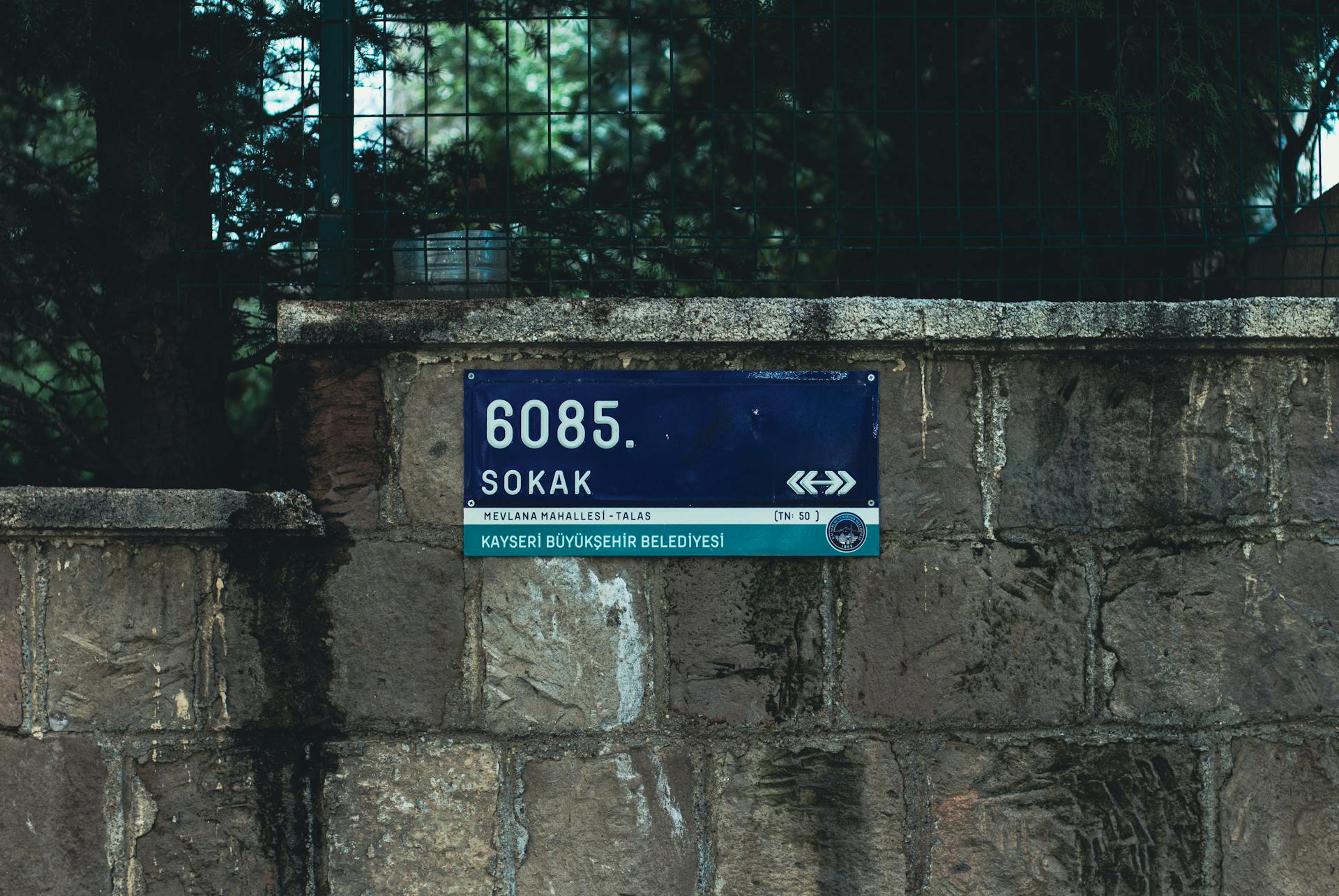 Blue street sign on a rustic stone wall in Talas, Kayseri, Turkey.