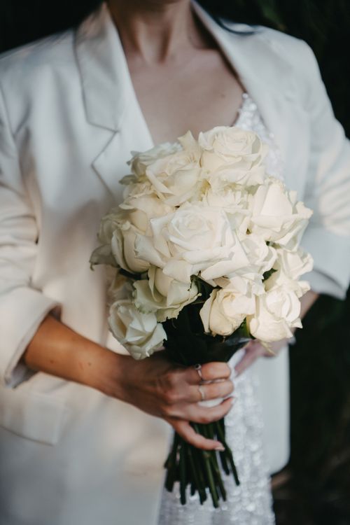 Free A woman holding a bouquet of white roses, perfect for weddings. Ideal for bridal styling. Stock Photo