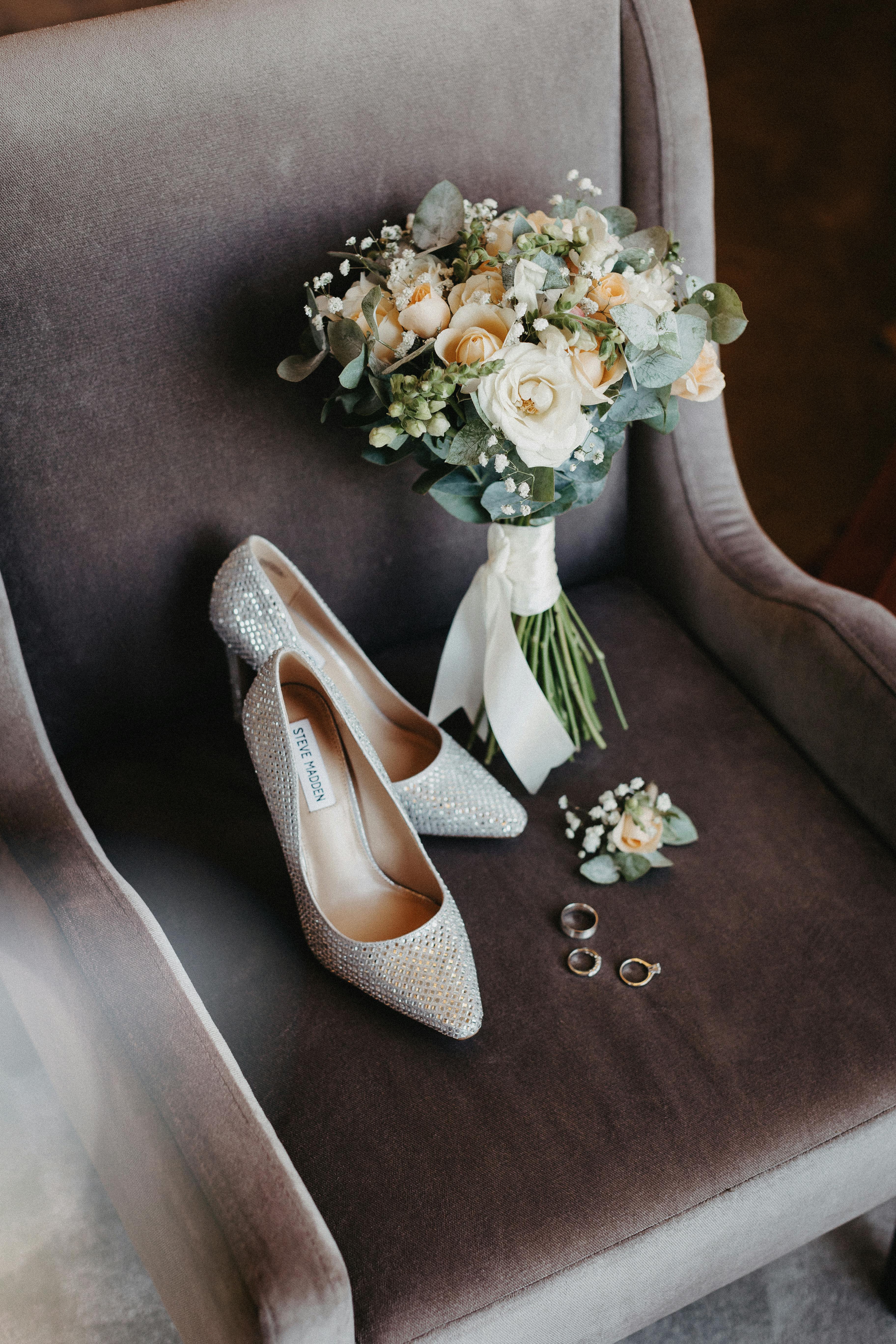 Free Stylish wedding shoes and floral bouquet on a chair with rings, creating a romantic atmosphere. Stock Photo
