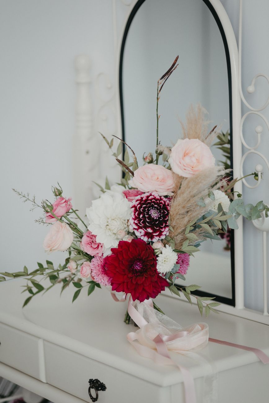 Bouquet with pink and red flowers elegantly displayed on a dresser with a mirror.