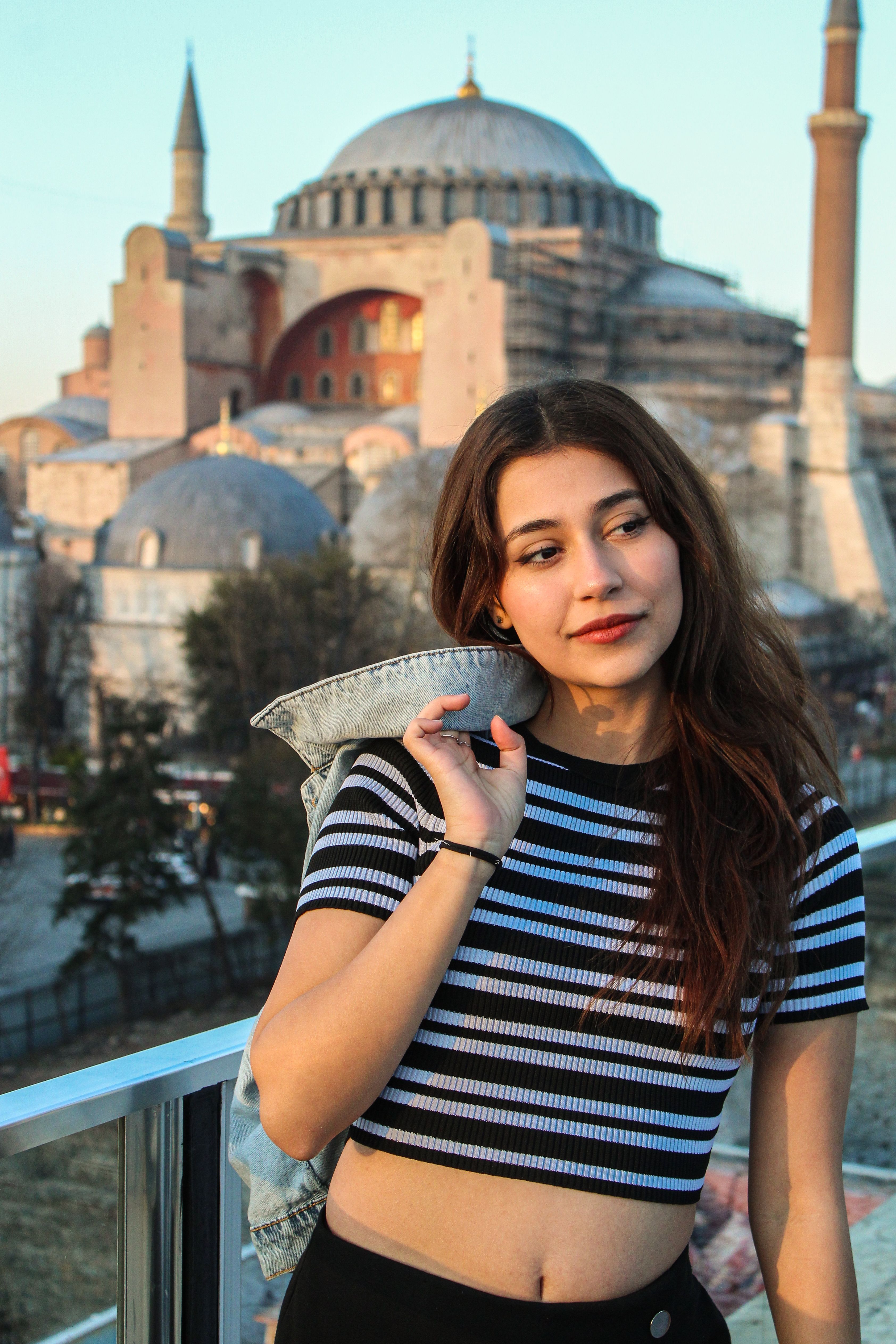 A stylish young woman stands in front of the iconic Hagia Sophia in Istanbul, Turkey.