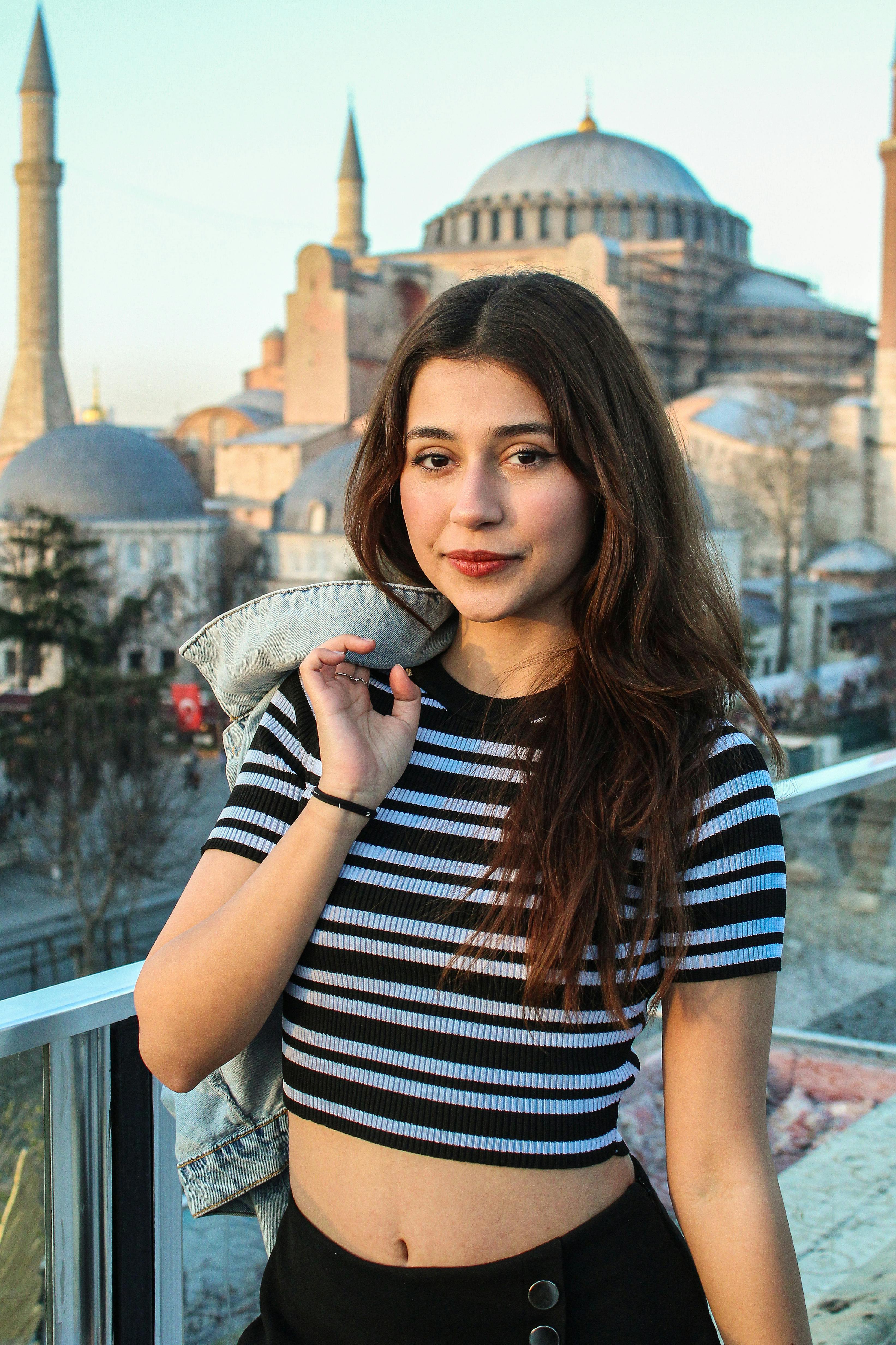 Young woman posing with Hagia Sophia backdrop in Istanbul, vibrant and modern.
