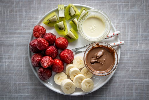 A vibrant fruit platter featuring strawberries, bananas, and kiwi with white and milk chocolate dips.