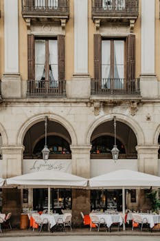 Outdoor cafe with elegant arches in historic Barcelona's vibrant square.