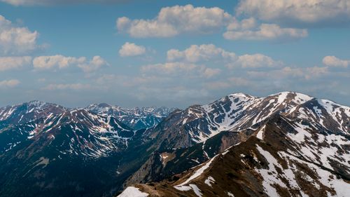 Free Stunning snow-capped mountains beneath a clear blue sky with scattered clouds, perfect for nature enthusiasts. Stock Photo