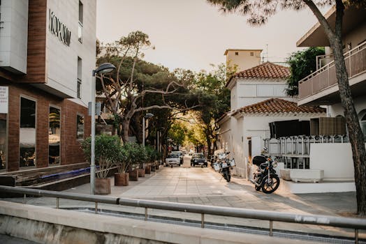 A tranquil urban street scene with motorcycles, lush greenery, and charming architecture at sunset.