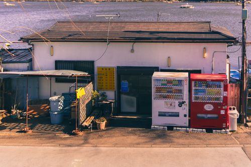 Free Japanese vending machines in front of a small shop by a tranquil lakeside during winter. Stock Photo