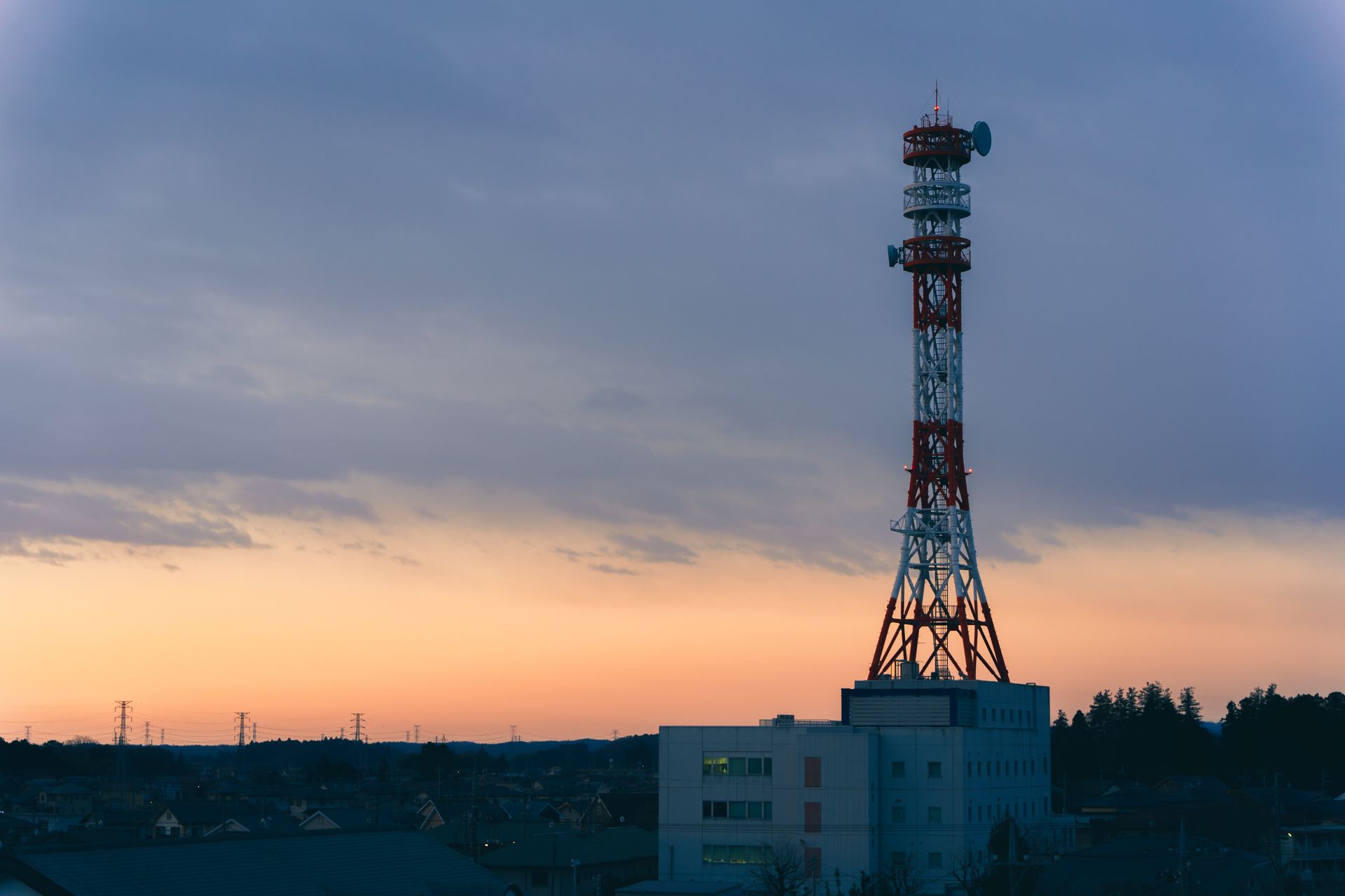 A tall communication tower stands against a colorful dusk sky, symbolizing modern connectivity.