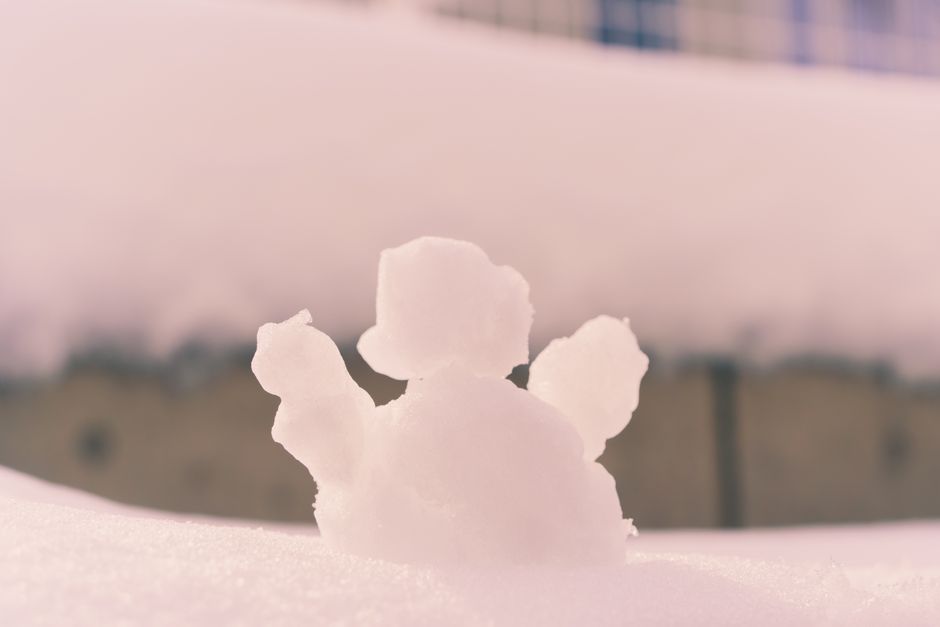 A small snow sculpture on a sunny winter day with soft pink hues.