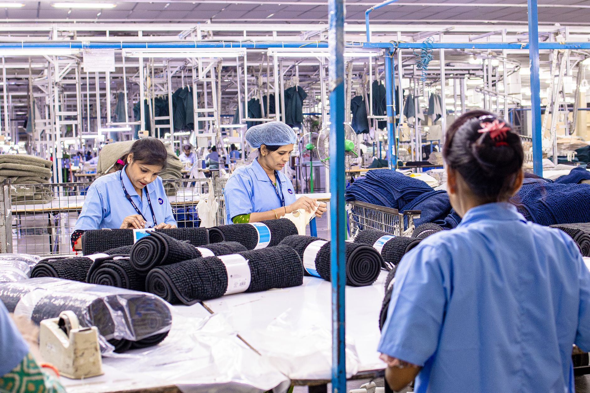 Female workers sorting fabric in a large textile factory setting, showcasing industry and teamwork.