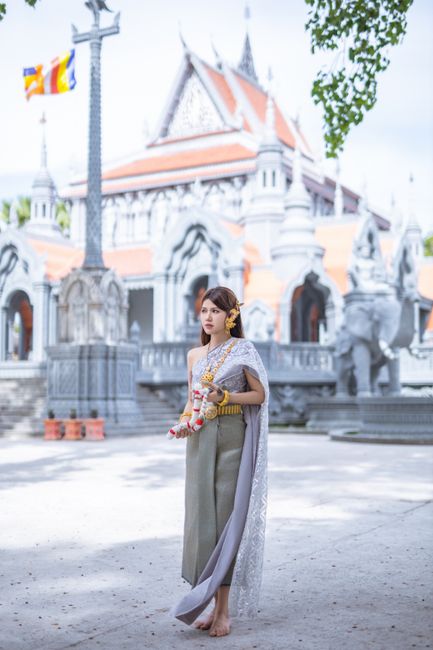 Woman in traditional Thai attire at a beautiful temple entrance.