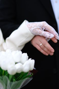 Bride and groom holding hands with bouquet of white tulips, symbolizing love and elegance.