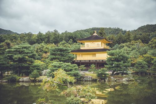 Free Serene view of Kinkaku-ji, the Golden Pavilion, surrounded by lush trees in Kyoto, Japan. Stock Photo