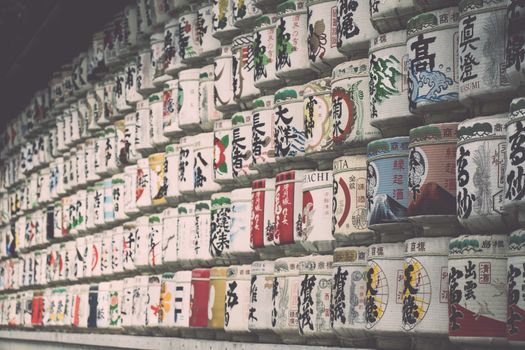 Rows of traditional Japanese sake barrels showcasing colorful labels.