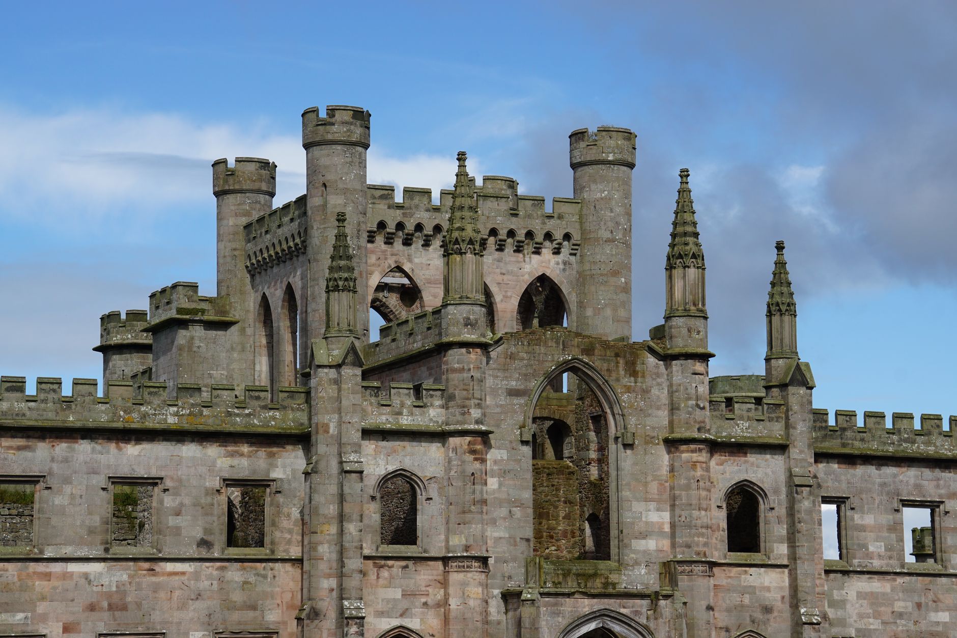 Stunning view of ancient castle ruins with gothic architecture under a clear blue sky. — free online jigsaw puzzle on JigsawPuzzlesFreeOnline.org