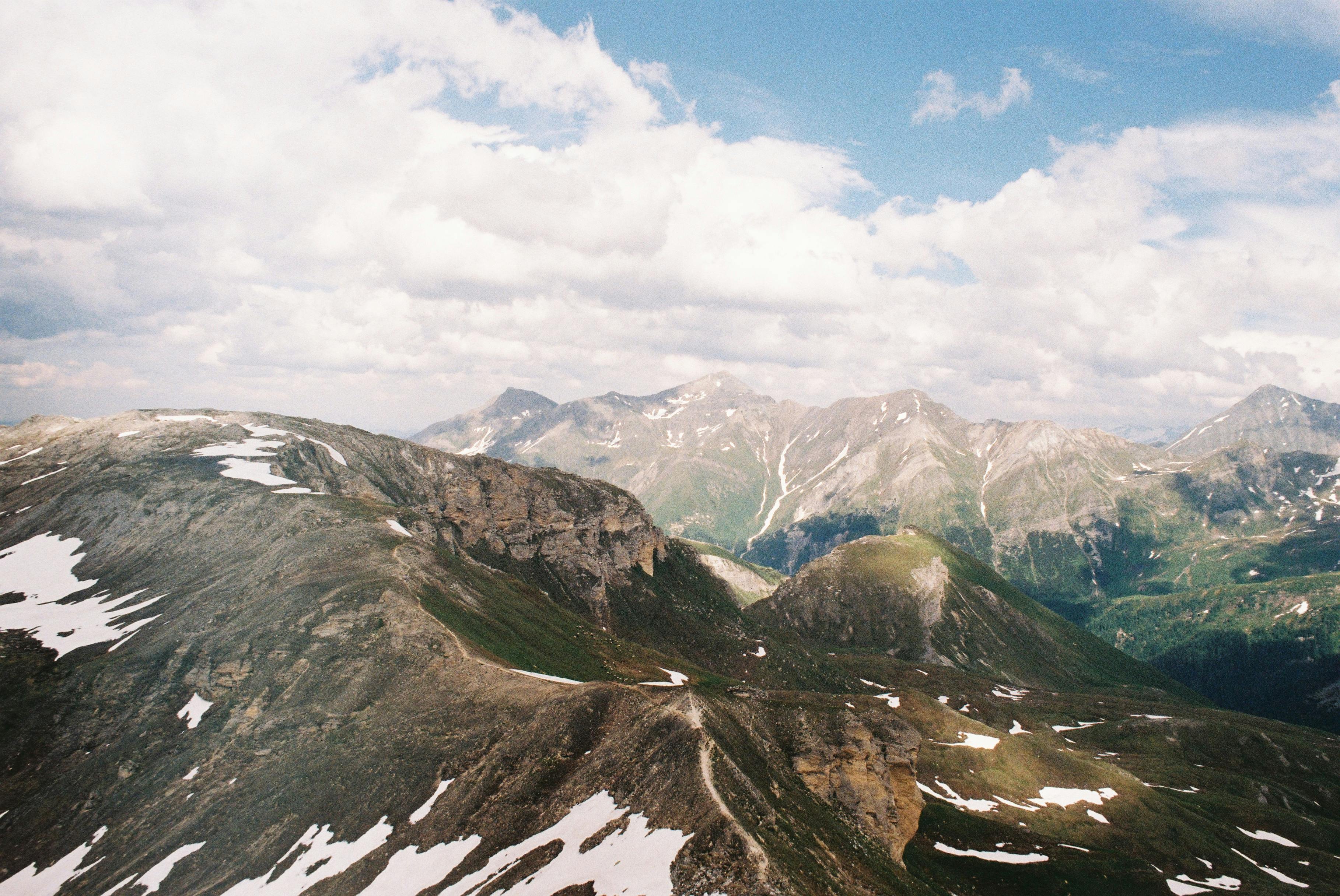 A breathtaking view of Austrian alpine mountains during summer with patches of snow.