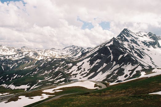 A breathtaking view of snow-capped peaks and lush valleys in Austria's Alps during springtime.