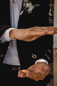 Close-up image of man hand gesturing in formal suit with black and white attire.