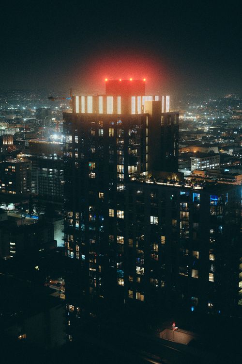 Free Dramatic aerial night view of a modern Los Angeles skyscraper glowing with city lights. Stock Photo