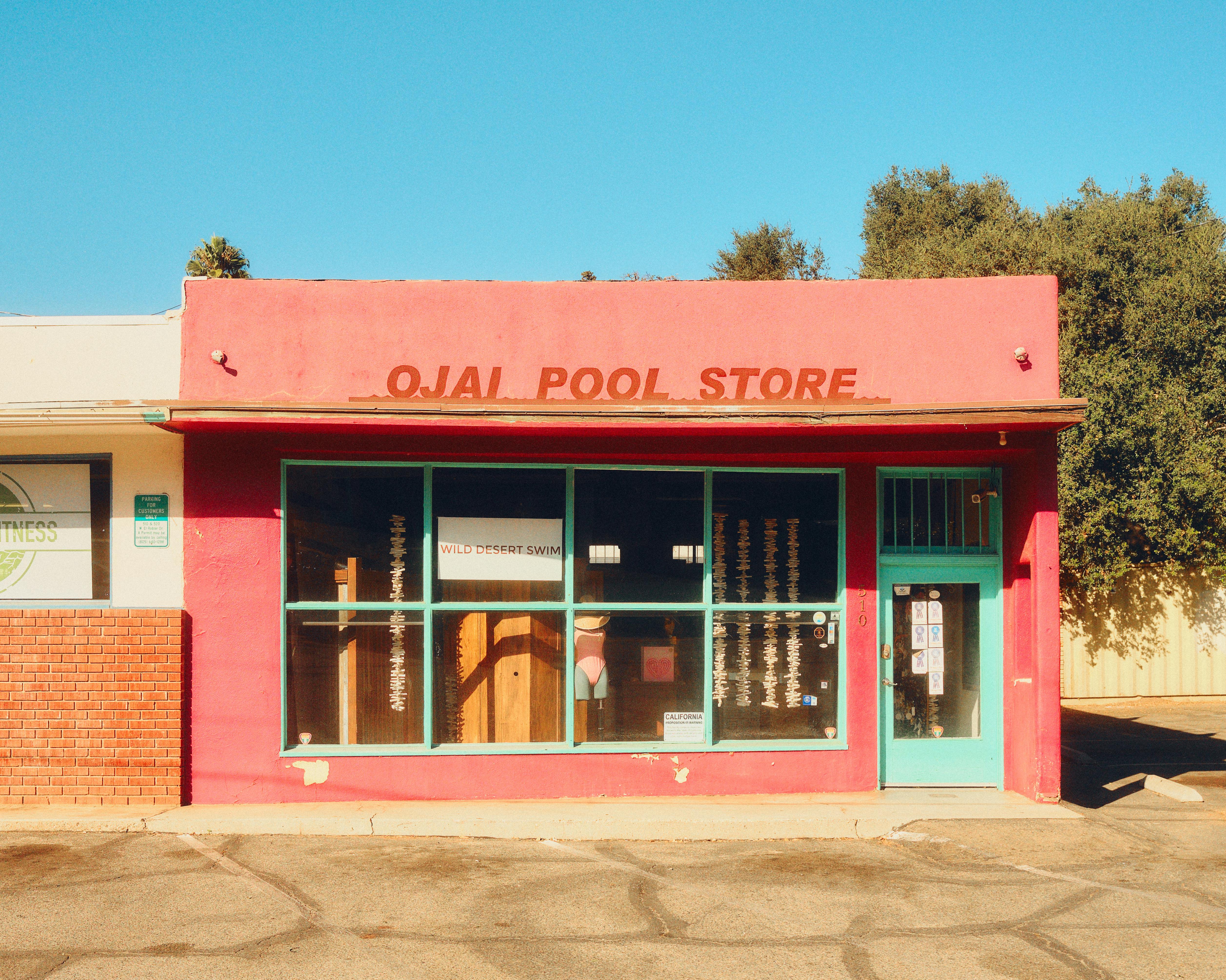 A vibrant red storefront of the Ojai Pool Store in California, showcasing retro architecture and design.