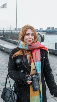 Young woman with a camera enjoying a snowy day by the waterfront.