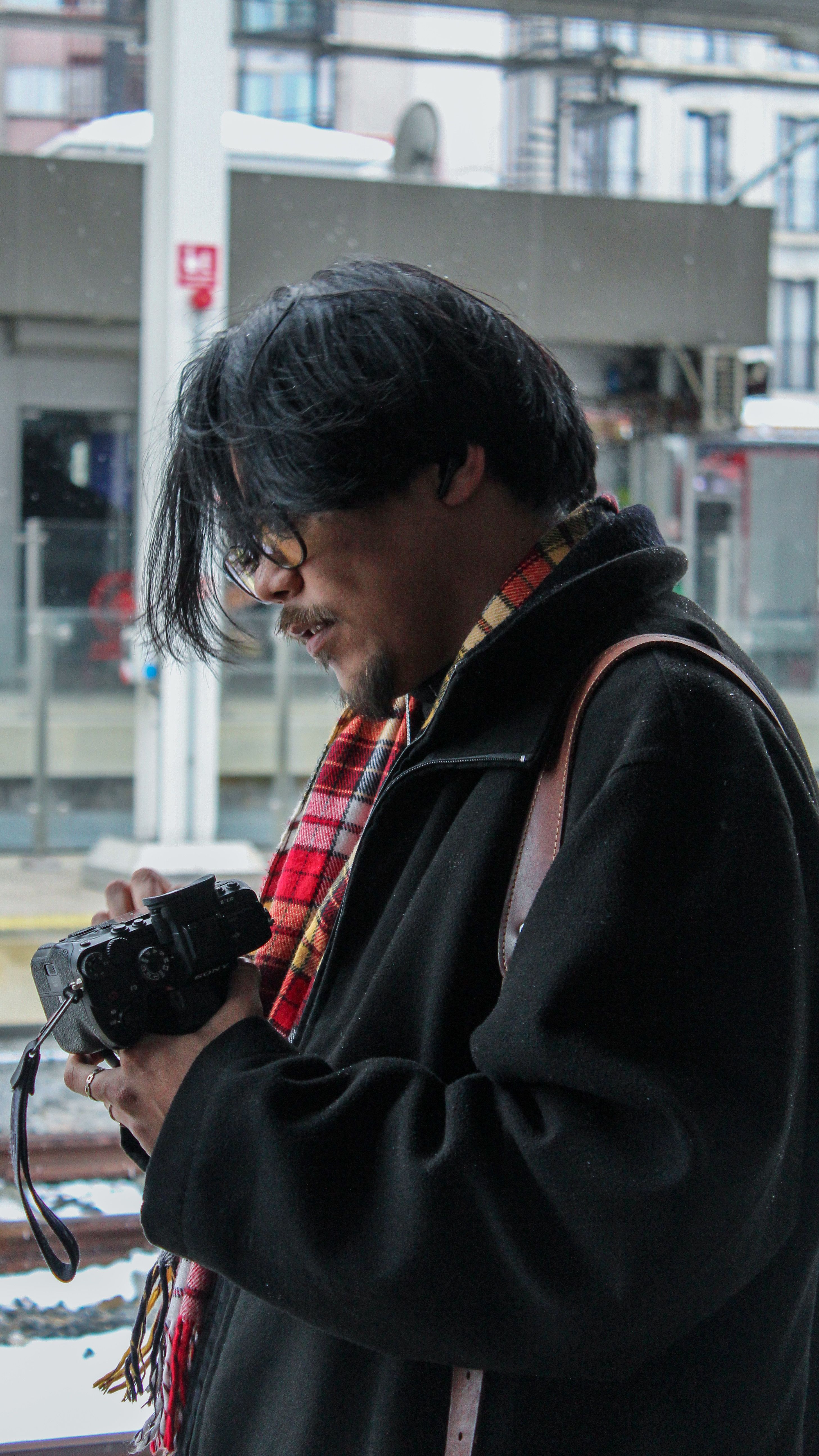 Young photographer examining a camera at a train station