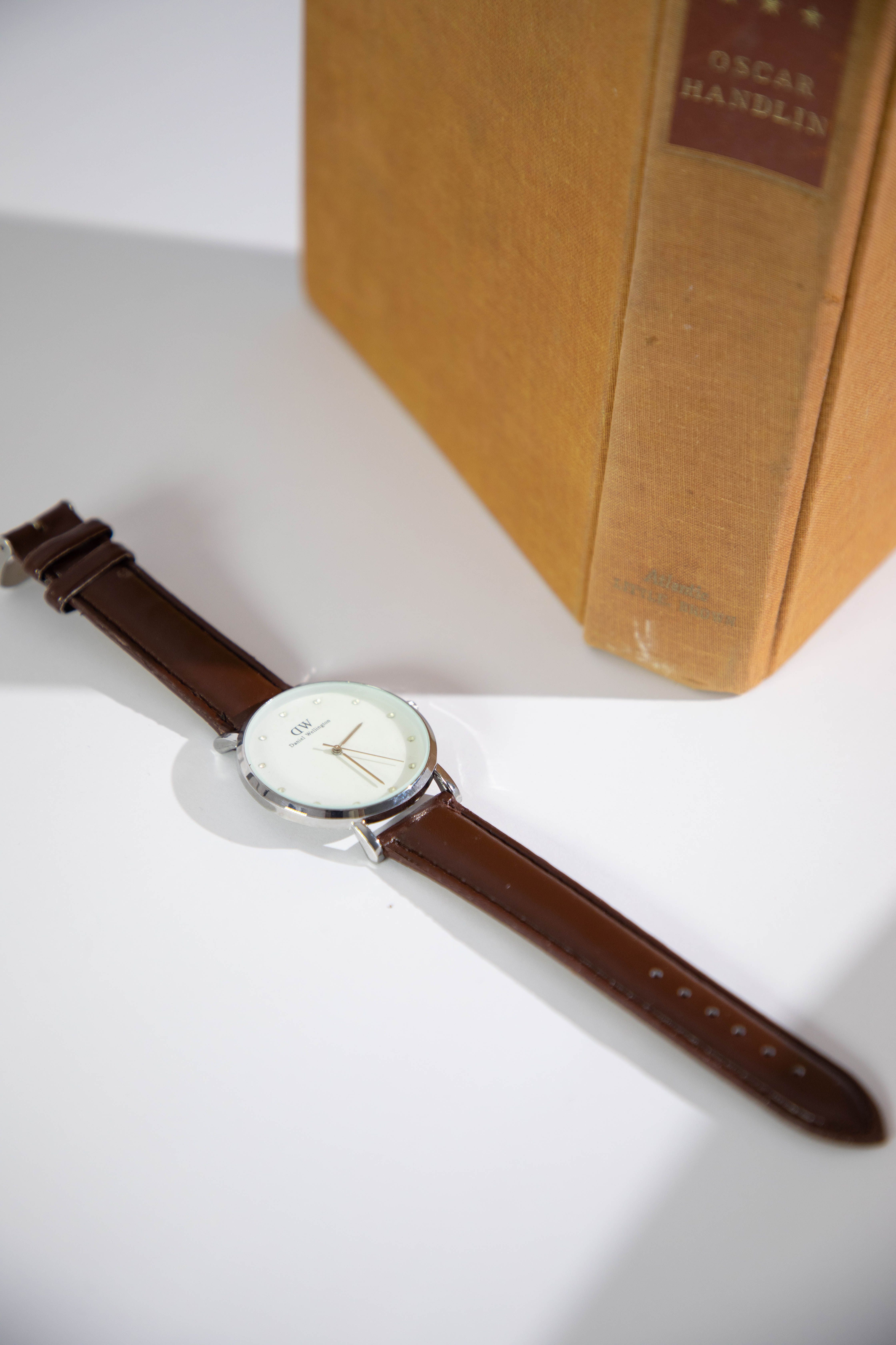 Rive field watch with brown strap beside a hardcover book