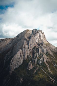 A striking mountain peak with rugged cliffs under a dramatic cloudy sky.