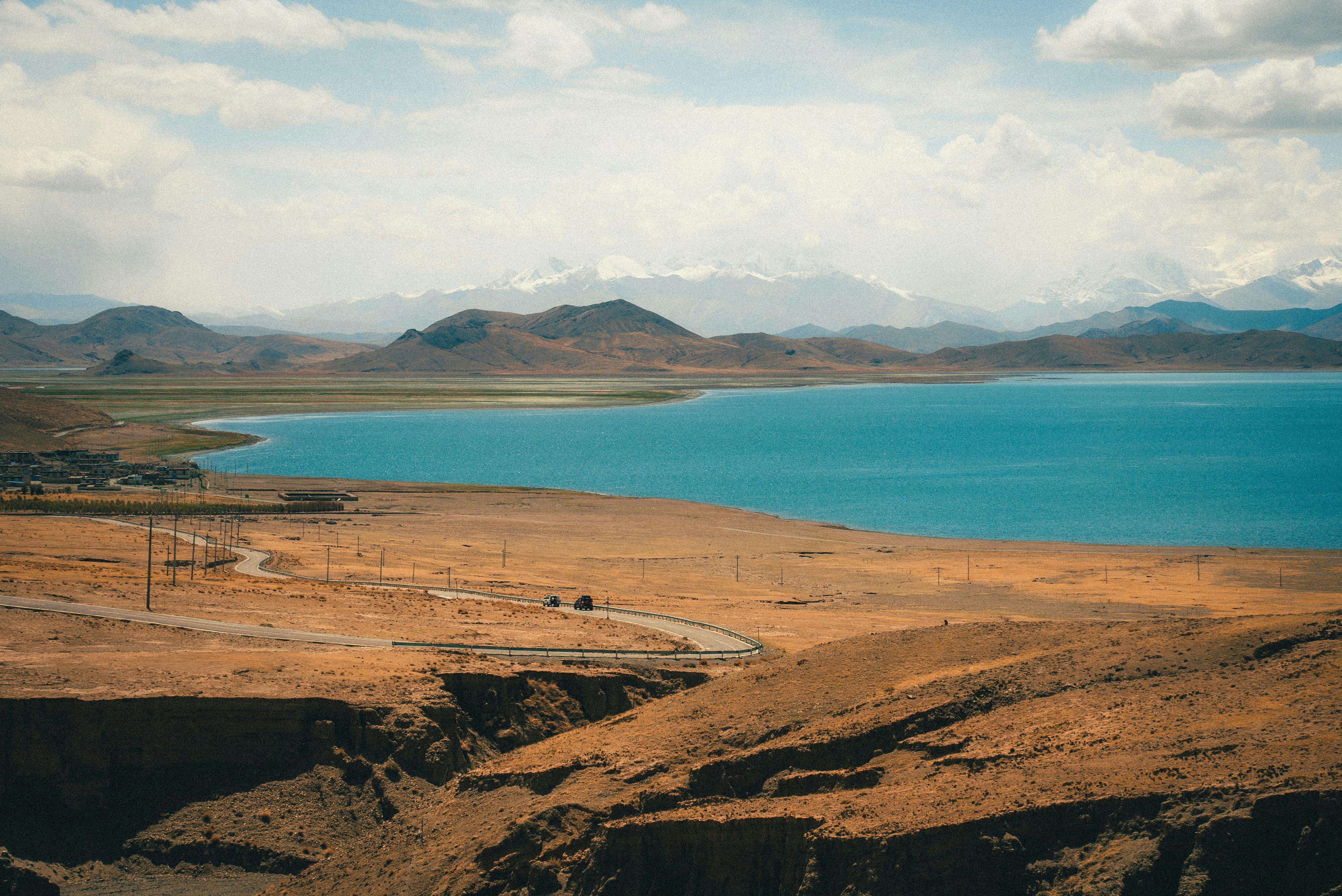 Expansive view of a tranquil mountain lake with clear blue water under a vibrant sky.