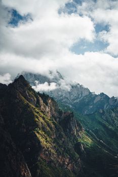 Explore mist-covered mountains with dramatic cliffs and lush green valleys under a cloudy sky.