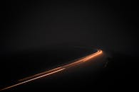 在旧金山的夜晚，长曝光照片捕捉到黑暗道路上移动汽车留下的迷人光条纹