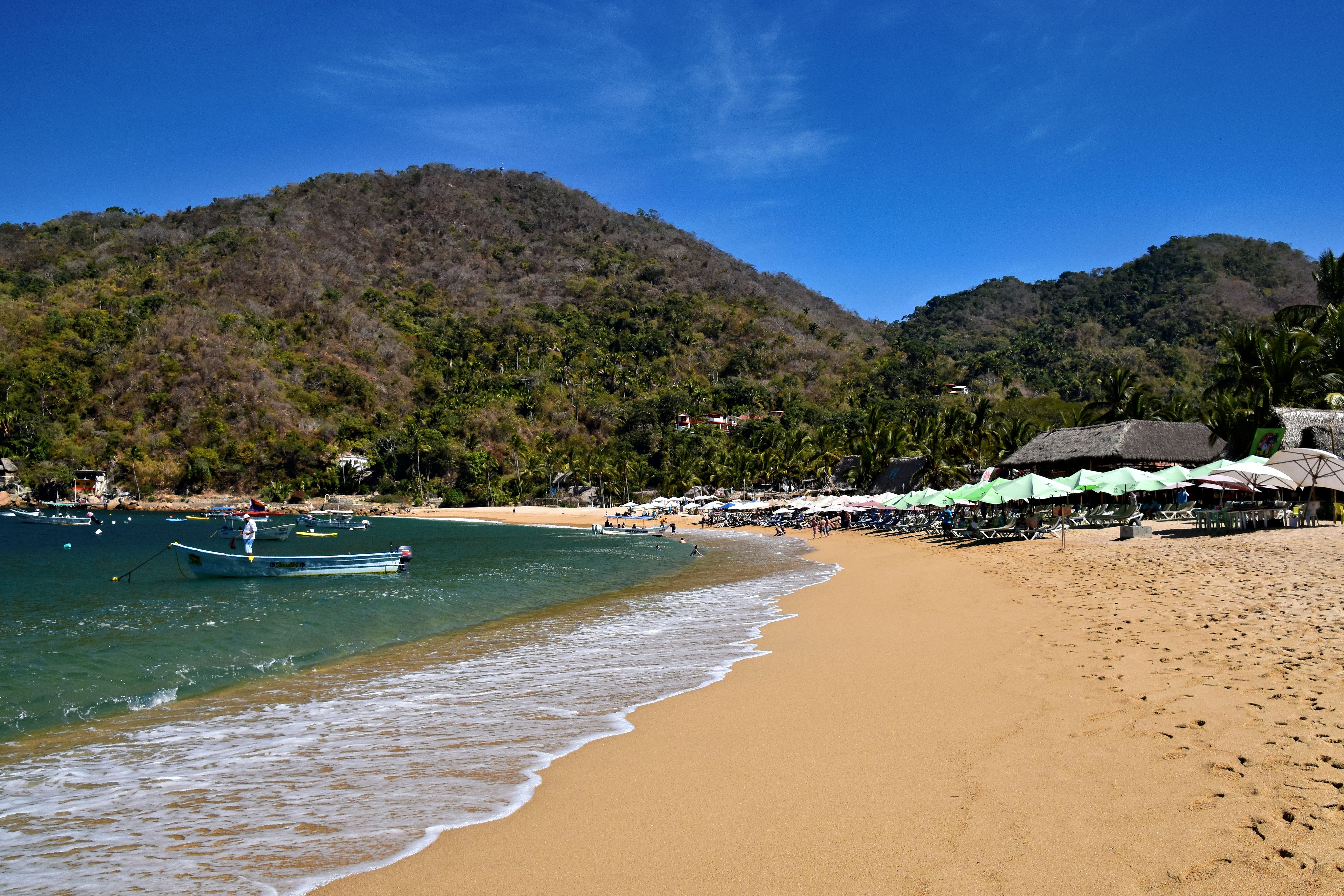 Sable doré, parasols de palapa et collines vertes à Yelapa, l’une des meilleures excursions depuis Puerto Vallarta