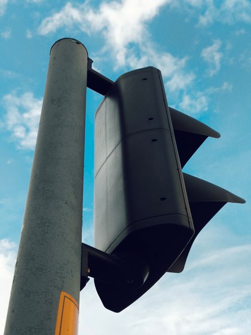 Free Close-up of a traffic light with blue sky and clouds background. Stock Photo