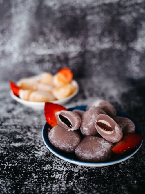 Free Close-up of assorted mochi desserts with fresh strawberry slices on a textured background. Stock Photo