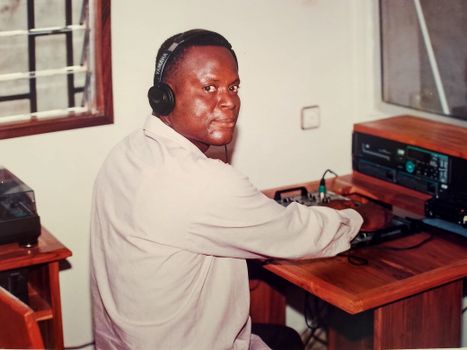 A man is wearing headphones and working with audio equipment in a home studio.