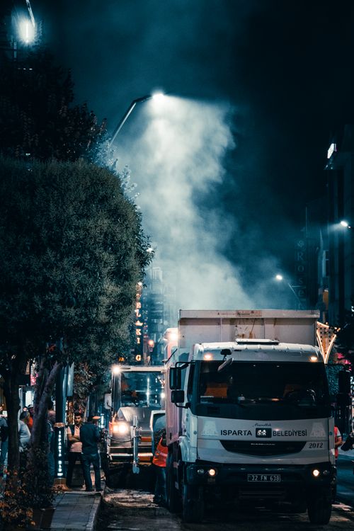 Free Street scene at night with trucks and atmospheric lighting in a city area. Stock Photo