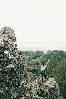 一名徒步旅行者站在维萨亚斯中部巴迪安的一座岩石山峰上，展示着自然美景与冒险精神