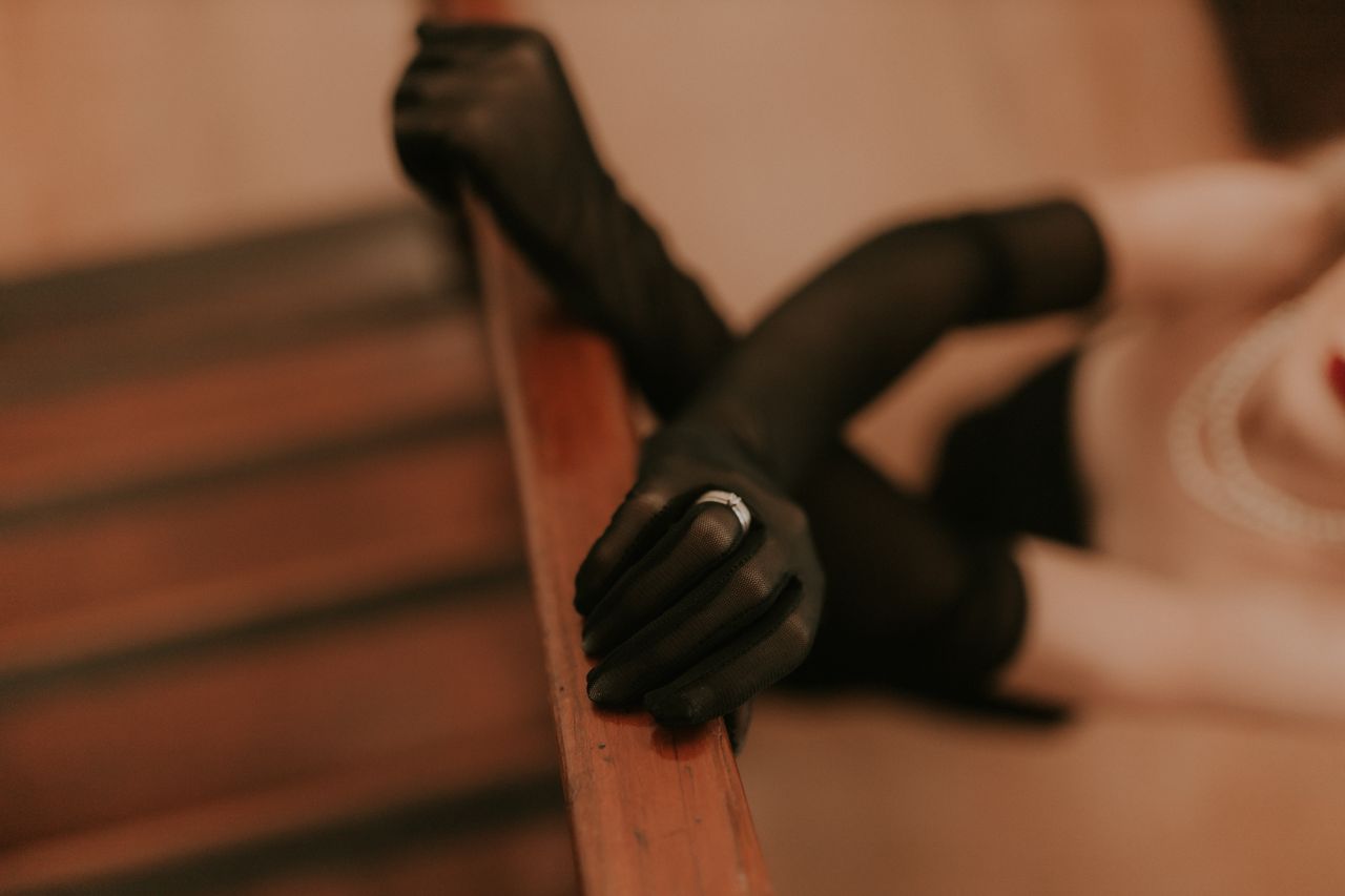 close up of a woman s gloved hands on stair railing in a vintage setti