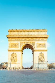 Vista del icónico Arco del Triunfo en París bajo un cielo azul claro.