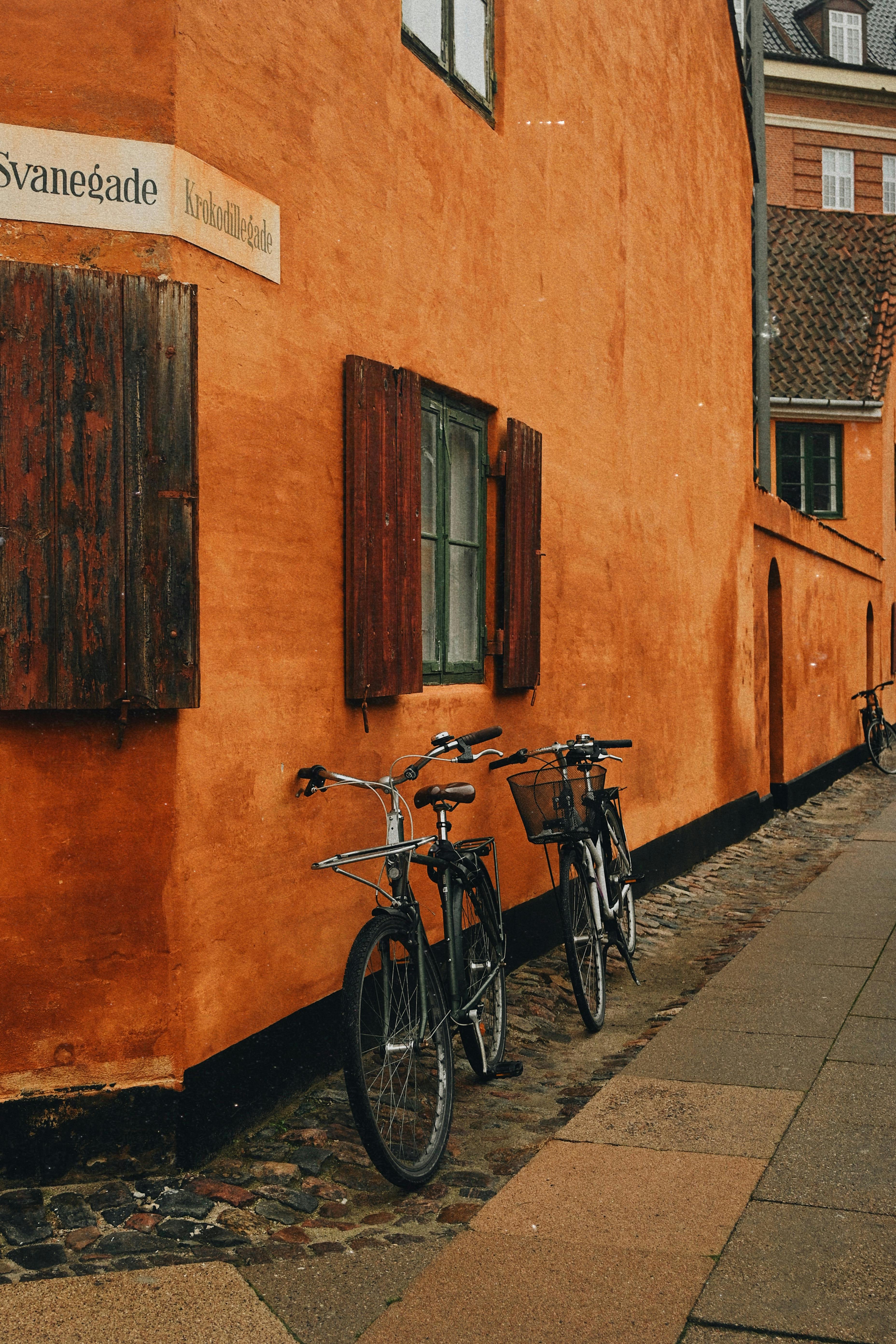 Picturesque street in Copenhagen featuring vibrant orange walls and vintage bicycles.