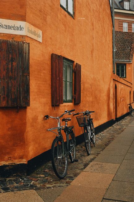 Picturesque street in Copenhagen featuring vibrant orange walls and vintage bicycles.